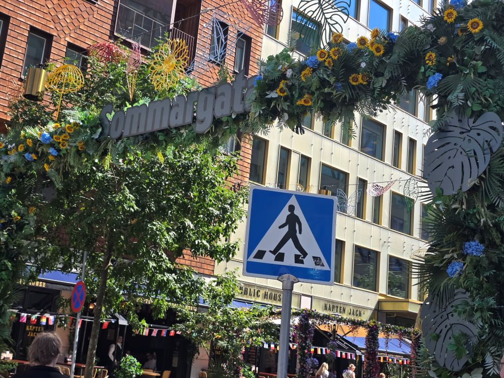 Sommerlich geschmückter Straßeneingang mit Blumen und bunten Dekorationen in Stockholm.