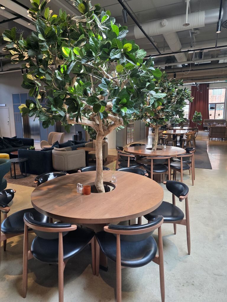 Großer Tisch mit Baum und Sitzplätzen im modernen Restaurantbereich unseres Hotels.