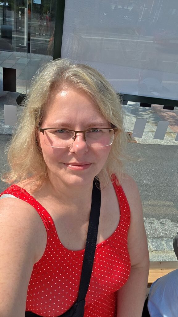 Frau in roten Kleid, beim Arten auf den Bus.