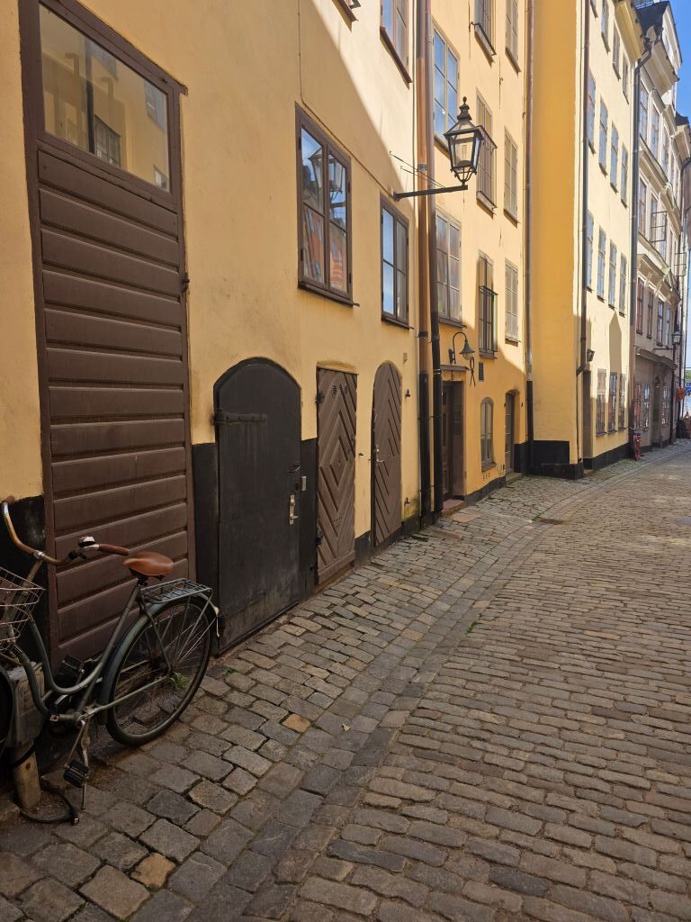 Schmale Kopfsteinpflastergasse mit gelben Häusern und Fahrrad in Gamla Stan in Stockholm.