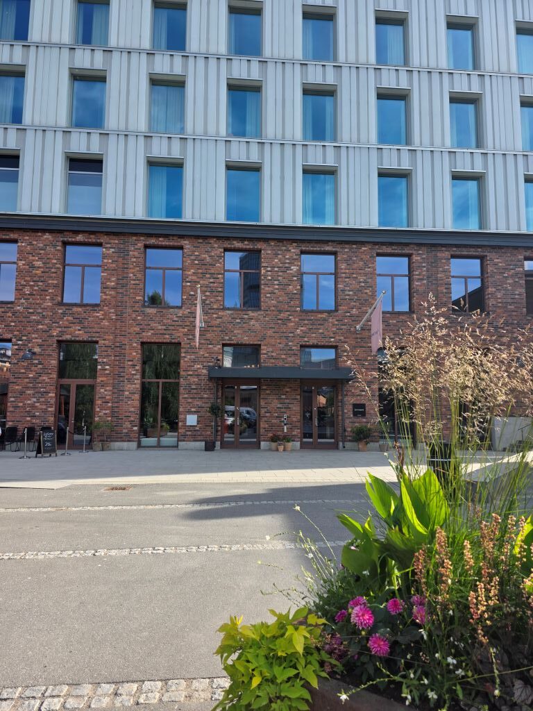 Außenansicht des Home Hotel Tapetfabriken mit Blumenbeet vor dem Eingang.