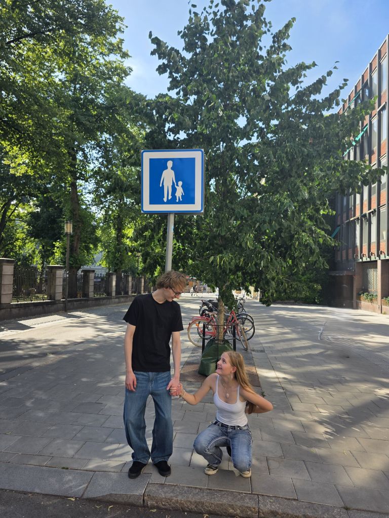 Zwei Jugendliche in Stockholm stellen gemeinsam das Motiv eines Fußgängerverkehrsschildes nach.