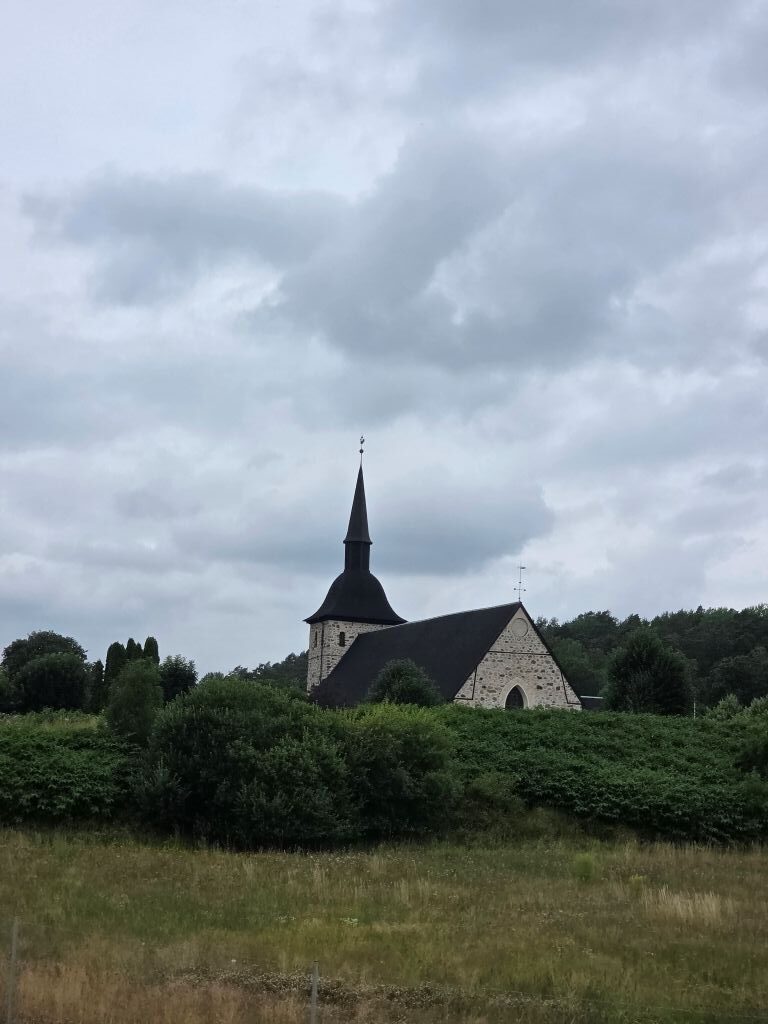 Schwedische Kirche am Straßenrand unter einem dicht bewölkten Himmel
