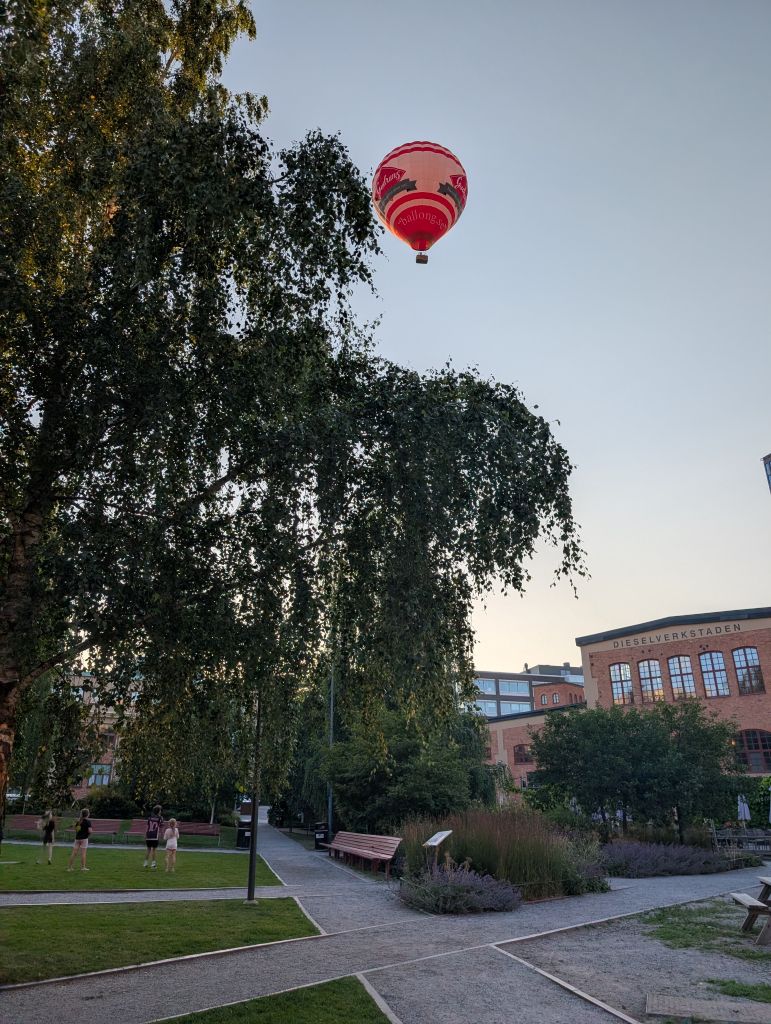 Heißluftballon über dem Park und den alten Backsteingebäuden in Sickla am Abend.