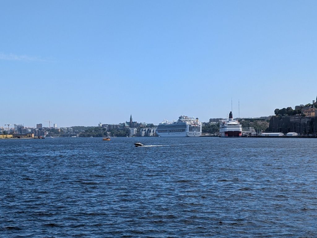 Blick über das Wasser in Stockholm mit Kreuzfahrtschiffen und Stadtansicht im Hintergrund.