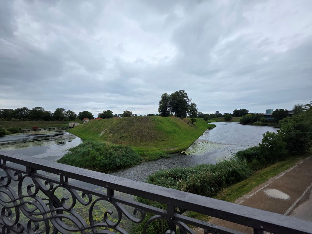 Grüne Wallanlagen mit Wassergraben in Kopenhagen bei bewölktem Himmel
