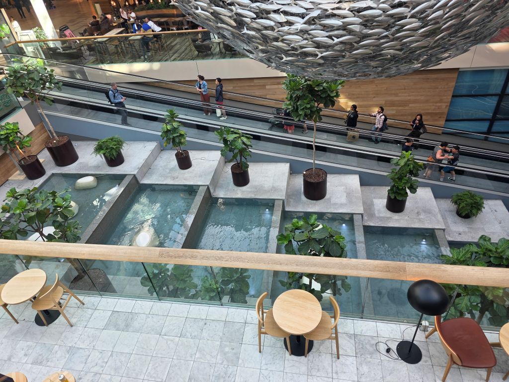 Innenbereich des Fisketorvet Copenhagen Mall mit Wasserbecken, Pflanzen und Rolltreppen