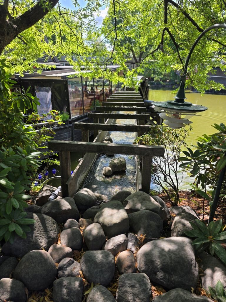 Kleine Wasseranlage zwischen Bäumen und Felsen im Tivoli Kopenhagen.