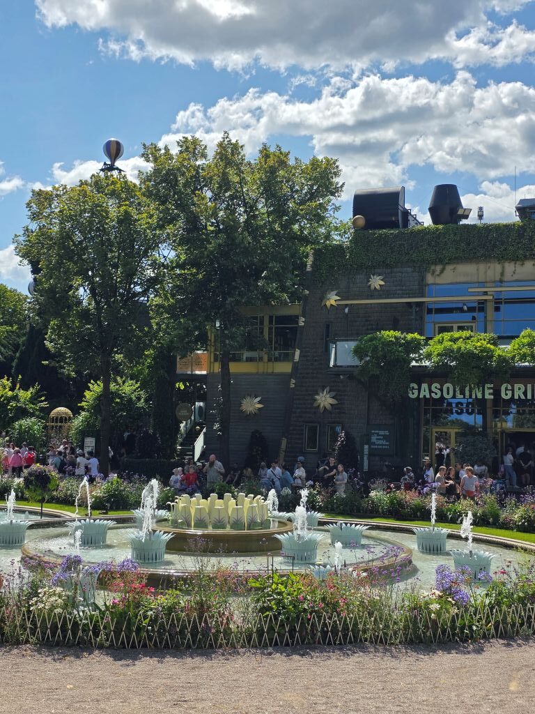 Springbrunnen und Blumenbeete vor einem Restaurant im Tivoli Kopenhagen.