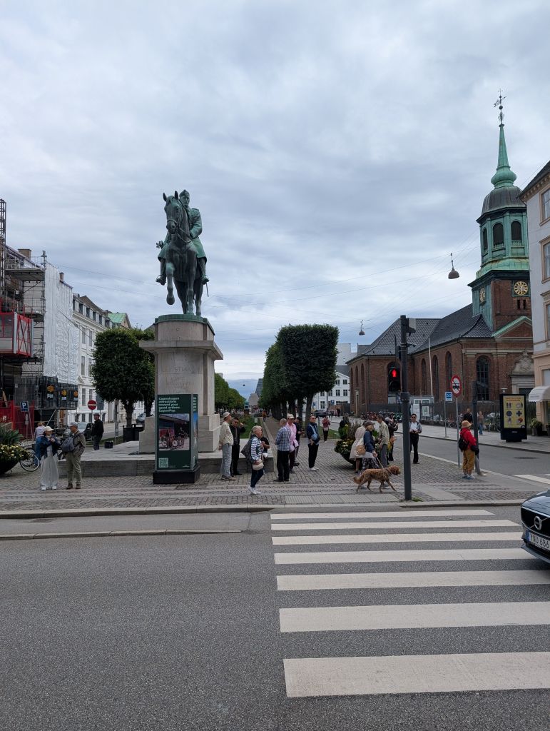 Reiterstandbild in einer Straße von Kopenhagen mit historischem Kirchturm im Hintergrund