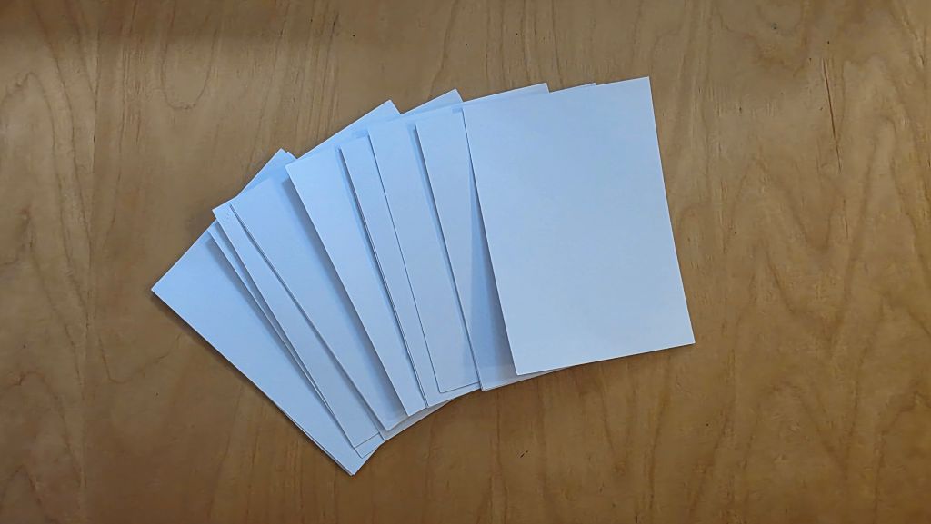 Zugeschnittene weiße Kartonstücke für die selbst gebastelten Konfirmationskarten.