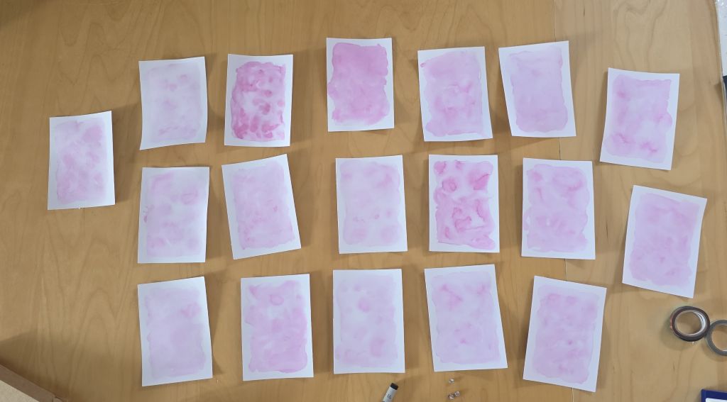 Mehrere rosa Aquarellhintergründe für die selbst gebastelten Konfirmationskarten beim Trocknen.