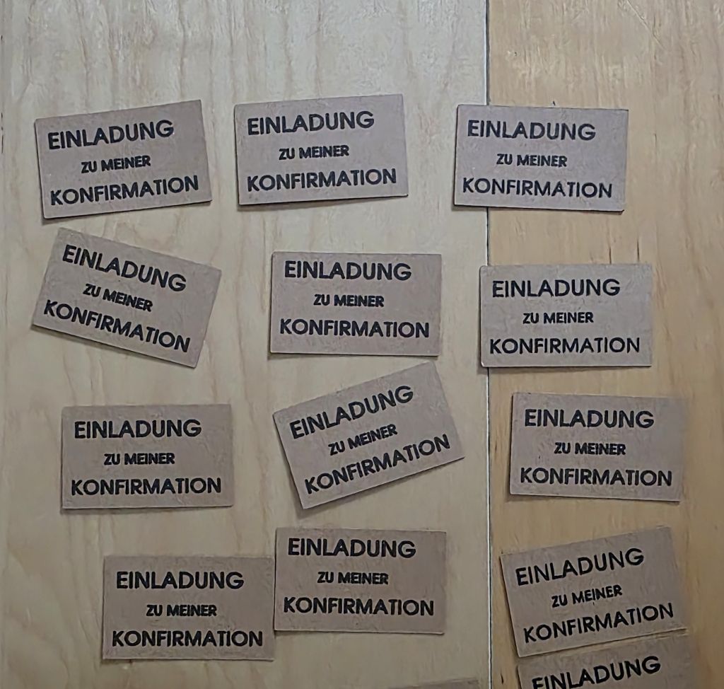 Geplottete Schriftzüge „Einladung zu meiner Konfirmation“ auf kleinen Rechtecken aus Kraftpapier.