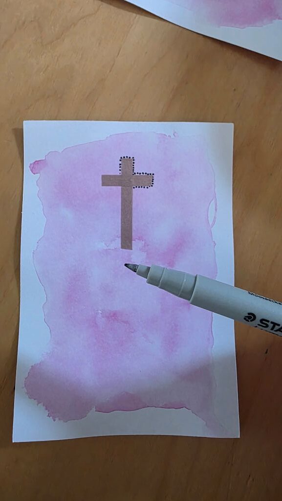 Schwarze Punkte werden mit einem Fineliner rund um das Kreuz auf der Konfirmationskarte gesetzt.