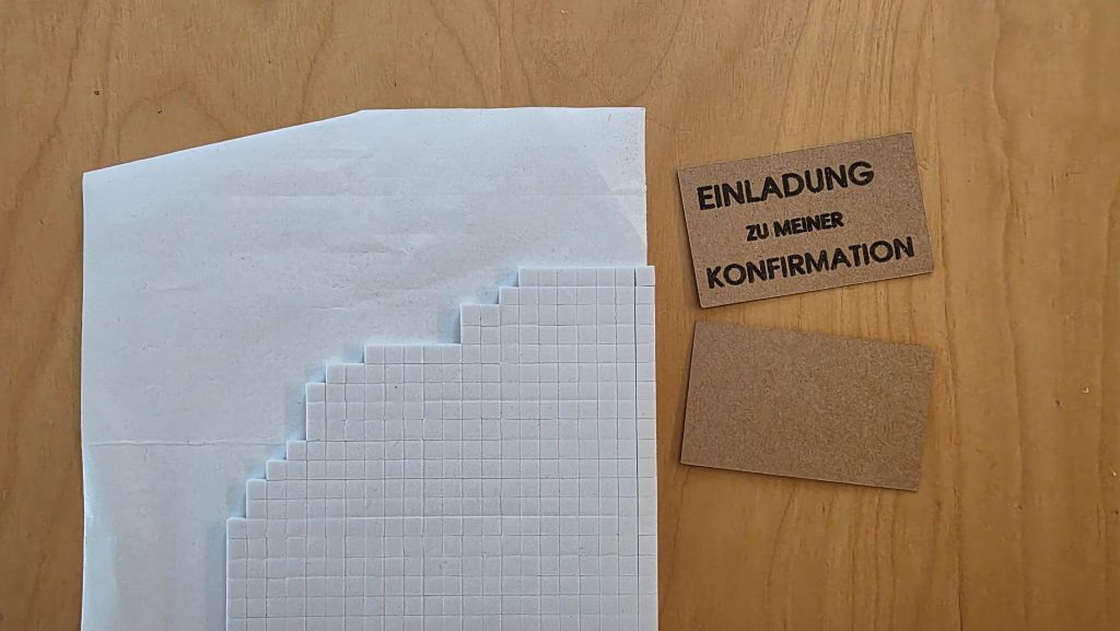 3D-Abstandsklebepads für den Schriftzug „Einladung zu meiner Konfirmation“ aus Kraftpapier.