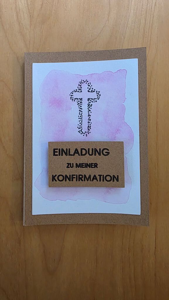 Einladungskarte zur Konfirmation mit rosa Aquarell, gepunktetem Kreuz und erhöhtem Schriftzug aus Kraftpapier.