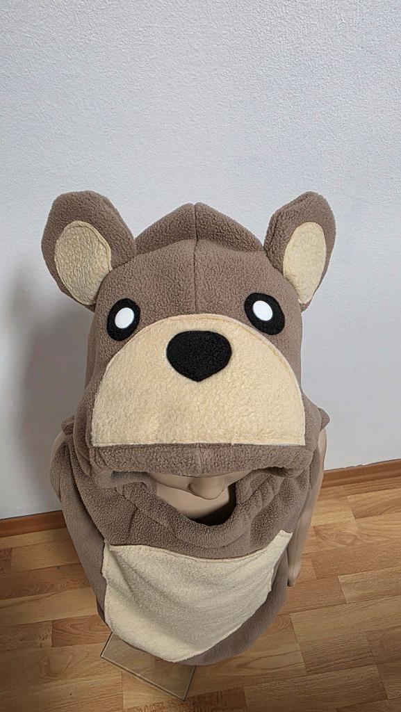 Blick von oben auf das handgefertigte Bärenkostüm für Kinder mit niedlichem Bärengesicht, großen Ohren und beigefarbenem Bauch aus weichem Fleece.